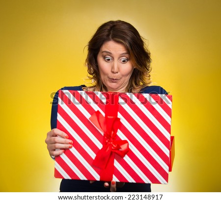 Portrait happy excited middle aged woman opening red gift box, very pleased surprised grateful with what she received isolated yellow background. Positive emotion facial expression feeling attitude