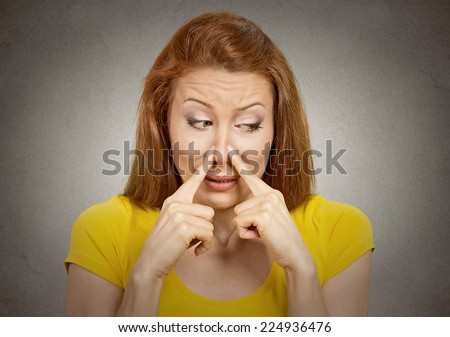 Closeup portrait headshot woman pinches nose with fingers hands looks with disgust away something stinks bad smell situation isolated grey wall background. Human face expression body language reaction