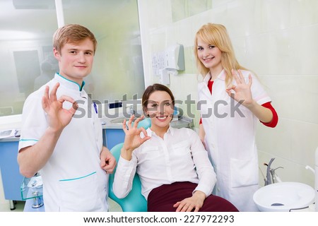 Group portrait happy male health care professional dentist assistant satisfied smiling woman patient in office giving thumbs up sign gesture. Successful treatment procedure outcome. Positive emotion