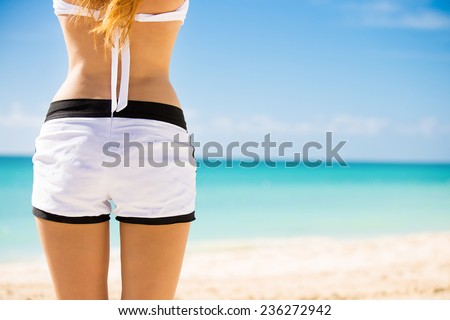 Back view cropped image woman sunbathing at tropical beach looking view of ocean on hot summer day. Vacation paradise nature getaway travel escape concept