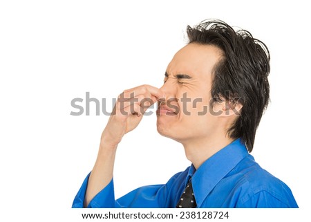 Closeup side view portrait young man disgust on his face pinches his nose, something stinks, very bad smell, situation isolated white background with copy space. Negative emotion expression feeling