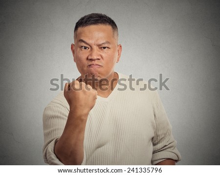 Portrait angry middle aged man fist up isolated on grey wall background. Negative human face expression, emotion, feelings, body language