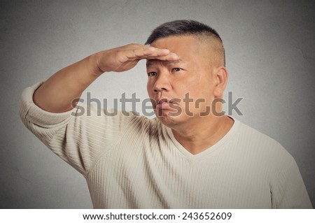 Curious middle aged man searching looking far away into future monitoring isolated grey wall background. Human face expression emotion body language. Future forecast search vision perception concept