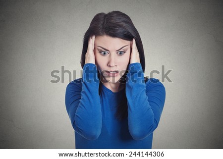 Closeup portrait headshot stressed sad young housewife, woman, employee having migraine, tension headache looking down isolated grey wall background. Human face expression emotion reaction, attitude