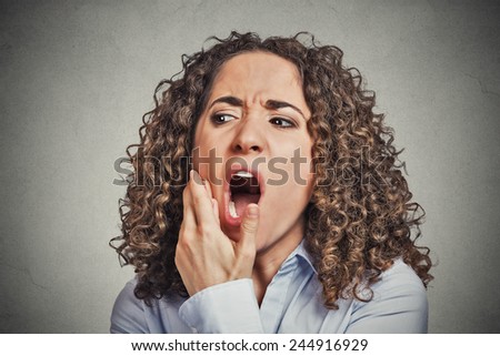 Closeup portrait young woman with sensitive tooth ache crown problem about to cry from pain touching outside mouth with hand isolated grey wall background. Negative emotion facial expression feeling