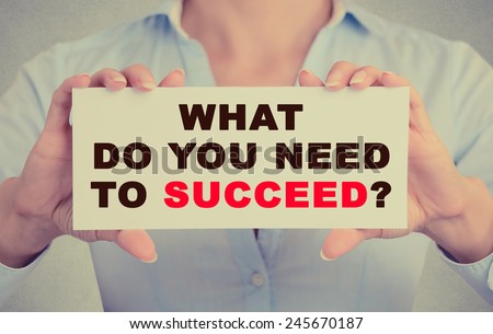 Businesswoman hands holding white card sign with what do you need to succeed question text message isolated on grey wall office background. Retro instagram style image
