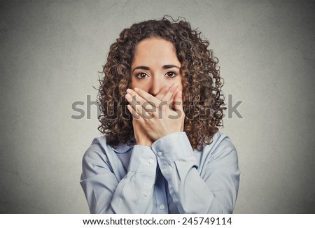 Closeup portrait young woman covering closed mouth with hands. Speak no evil concept isolated grey wall background. Human emotion face expression sign symbol. Media news employee relationship coverup