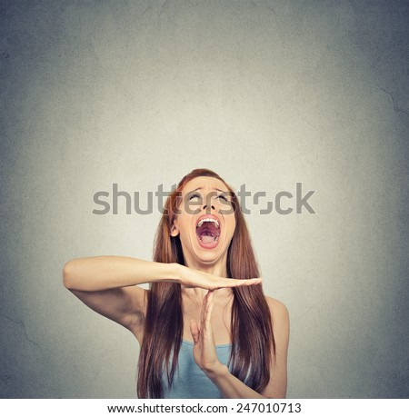 Young woman showing time out hand gesture, frustrated screaming to stop isolated on grey wall background. Too many things to do. Human emotions face expression reaction