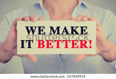 Businesswoman hands holding white card sign with we make it better text message isolated on grey wall office background. Retro instagram style image