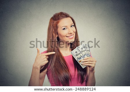 Closeup portrait super happy excited successful young business woman holding money dollar bills in hand isolated grey wall background. Positive emotion facial expression feeling. Financial reward