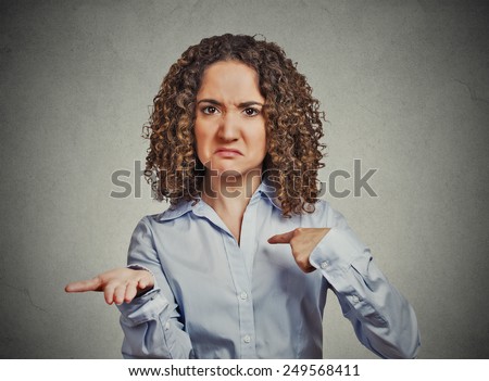 Closeup portrait young woman gesturing with hand palms up to pay back now bills money isolated grey wall background. Negative human emotion facial expression feeling reaction body language