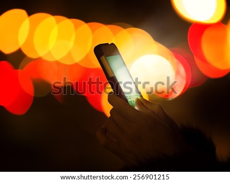 Woman hands using mobile smart phone with glowing screen isolated on street night light with colorful bokeh background