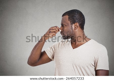 Closeup side profile portrait of man with disgust on face pinches his nose something stinks bad smell situation isolated grey background. Negative emotion facial expression, perception body language