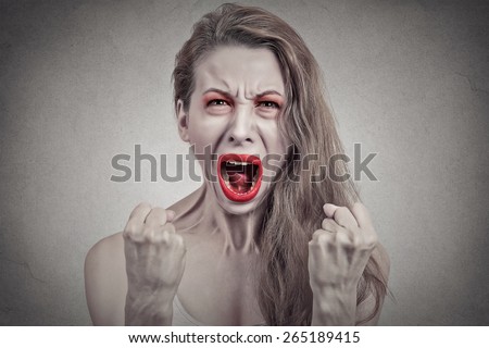 Screaming girl. Closeup portrait angry young woman hysterical having nervous breakdown fists up in air isolated on grey wall background. Negative human emotion facial expression feeling