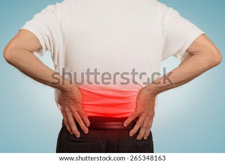 rear view old man grandpa holding his painful lower back colored in red with hands isolated on light blue  background. Human health problems