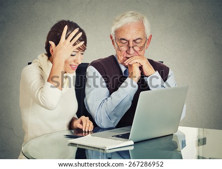 Young woman teaching confused, senior, older, elderly man with eyeglasses how to use laptop. Generation gap differences concept