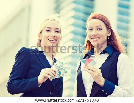 Closeup portrait happy smiling young businesswomen with credit cards and cash on hands, convenience of electronic money isolated corporate office background. Financial decision, banking system concept