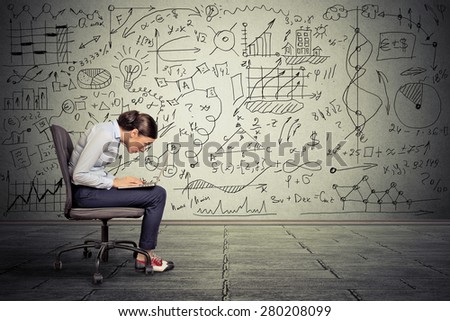 Young serious woman working on computer sitting on chair