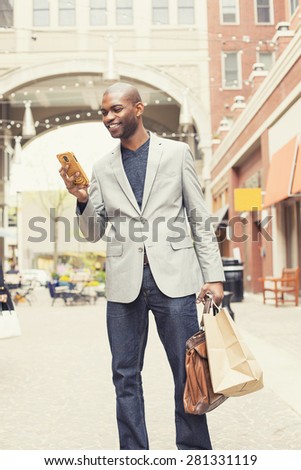 Happy smiling shopping man texting on his phone at a store