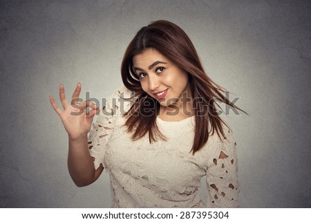Beautiful young woman showing Ok sign isolated on gray wall background. Positive human emotions face expression body language