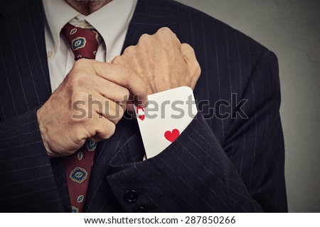 Closeup cropped image senior man hand pulling out a hidden ace from the sleeve isolated on gray wall background