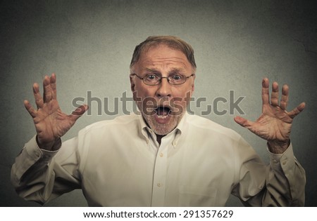 Closeup portrait shocked stunned surprised man eyes and mouth wide open, hands in air yelling screaming isolated on gray wall background. Negative human emotion facial expression feeling