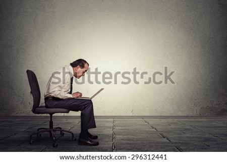 Portrait middle aged man working on laptop sitting on chair in empty office room
