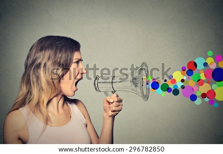 Portrait angry screaming young woman holding megaphone isolated on grey wall background. Negative face expression emotion feelings. Propaganda, breaking news, power, social media communication concept