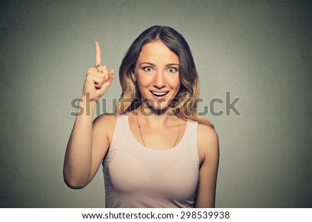 Portrait happy beautiful excited woman pointing with finger up isolated on grey wall background. Positive human face expressions, emotions, feelings body language, perception