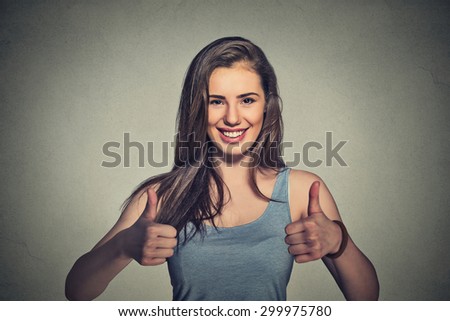 Happy female college student showing thumbs up isolated on gray wall background