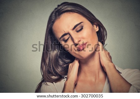 Back and spine disease. Closeup portrait tired woman massaging her painful neck isolated on gray wall background. Face expression