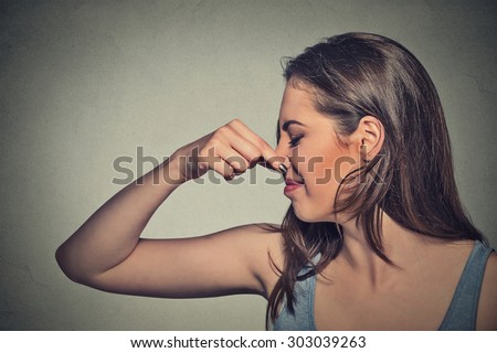 Side profile portrait headshot woman pinches nose with fingers looks with disgust away something stinks bad smell situation isolated gray wall background. Human face expression body language reaction