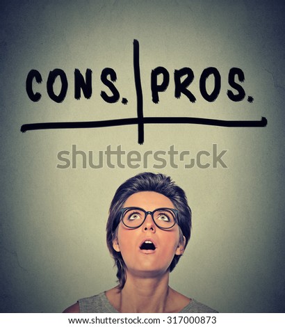 pros and cons, for and against argument concept. Young business woman with glasses looking up deciding isolated on gray wall background. Face expression, emotion, feeling, perception, vision, decision