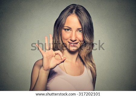 Portrait beautiful happy young woman showing Ok sign with hand isolated on gray wall background. Positive human emotions face expression body language