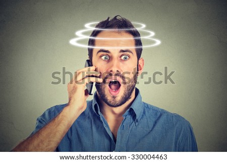 Head is spinning vertigo dizziness. Portrait shocked man talking on mobile phone. Bad news. Modern gadgets and health issues