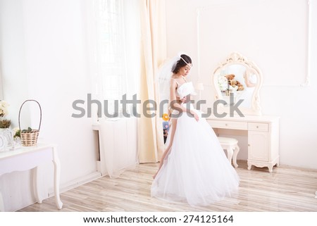Beautiful bride in lingerie with a beautiful figure trying wedding dress. Bride getting ready on her wedding day