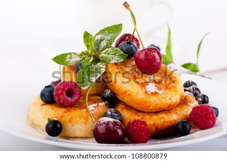 Cheese pancakes with forest berries and cup of coffee
