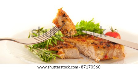 Meat, an onion and pepper on a grill, a fork with a knife