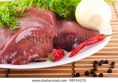 Pork liver with pepper and an onion on a bamboo board