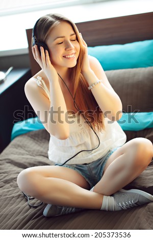 Young woman listening to music on bed at home
