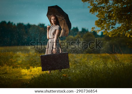 Young woman walking away with a suitcase under rain
