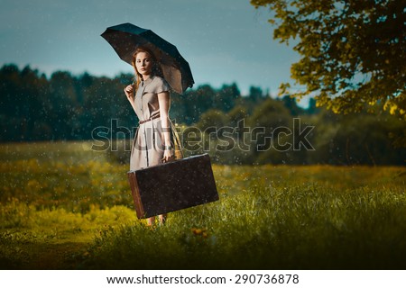 Young woman walking away with a suitcase under rain