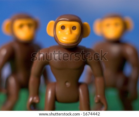 two out of focus toy monkeys behind a focused monkey