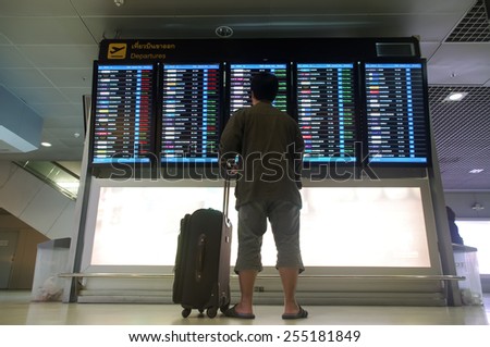 Bangkok, Thailand - December  5, 2014: Male  traveler with suitcase  is looking up information on flight departure board at Suvarnabhumi airport