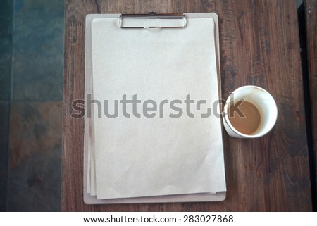 Clipboard with blank page and cup of coffee on wooden desk,Work at coffee shop.Photo in vintage style