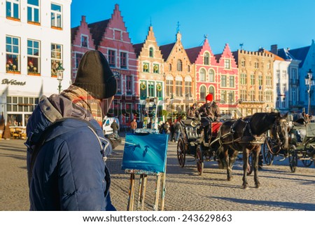 Bruges, Belgium - December 28, 2014: Street artist paints a picture of a Horse carriage waiting tourists on Grote Markt square of Brugge Christmas. Bruges is UNESCO world heritage listed for its