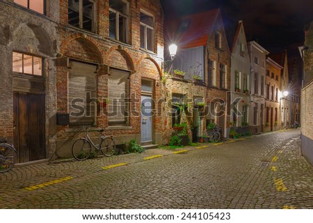 Scenic cityscape with the picturesque night medieval street with bike in Bruges, Belgium