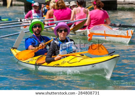 Venice, Veneto, Italy - May 24, 2015: Man and woman oarsmen in colorful hats in boat race along the Cannaregio Canal in the Venice Vogalonga regatta. More than 1,500 boats take part in the annual