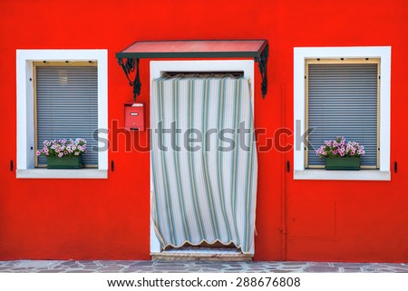 Colorful houses decorated with flowers, windows with shutters, close-up, famous island Burano, Venice, Italy