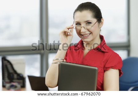 Woman with the red shirt in the office with a laptop